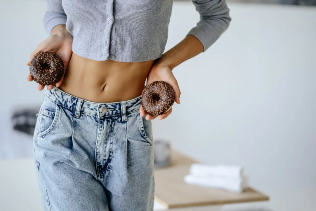 szczupla kobieta trzymająca pączki, pokazuje efekty działania tirzepatydu